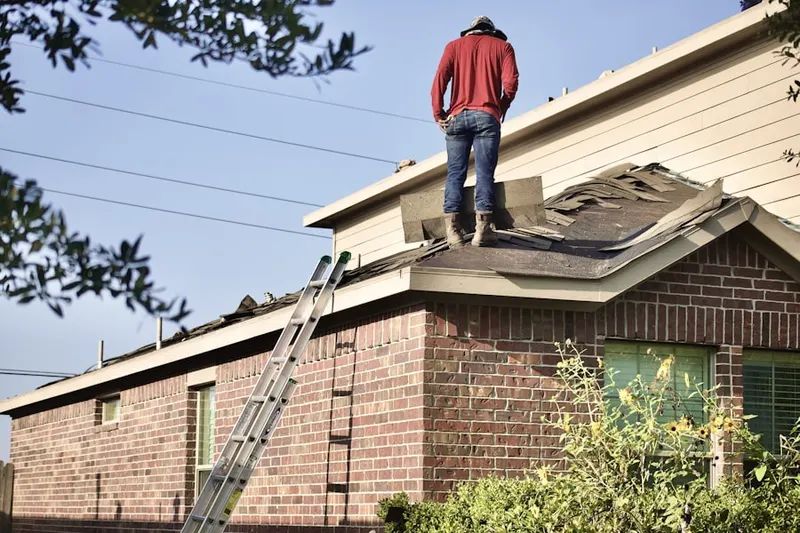 Professional roofer working on a residential roof in West Newton